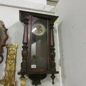 A mahogany wall clock with pendelum and key