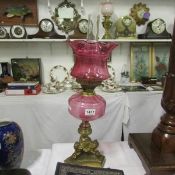 A Victorian brass oil lamp with cranberry glass font and later cranberry glass shade