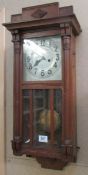 An oak wall clock with pendelum and key