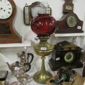 A brass oil lamp with ruby glass shade