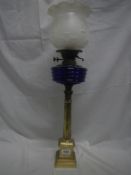 A brass Corinthian column oil lamp with blue glass font