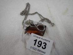 A silver chain and pendant set amber