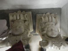 A pair of concrete cherub wall sconces