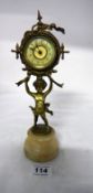 A small clock supported by a cherub on onyx base