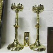 A pair of tall brass church candlesticks and a brass vase