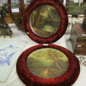 A pair of circular ceramic wall plaques in velvet frames