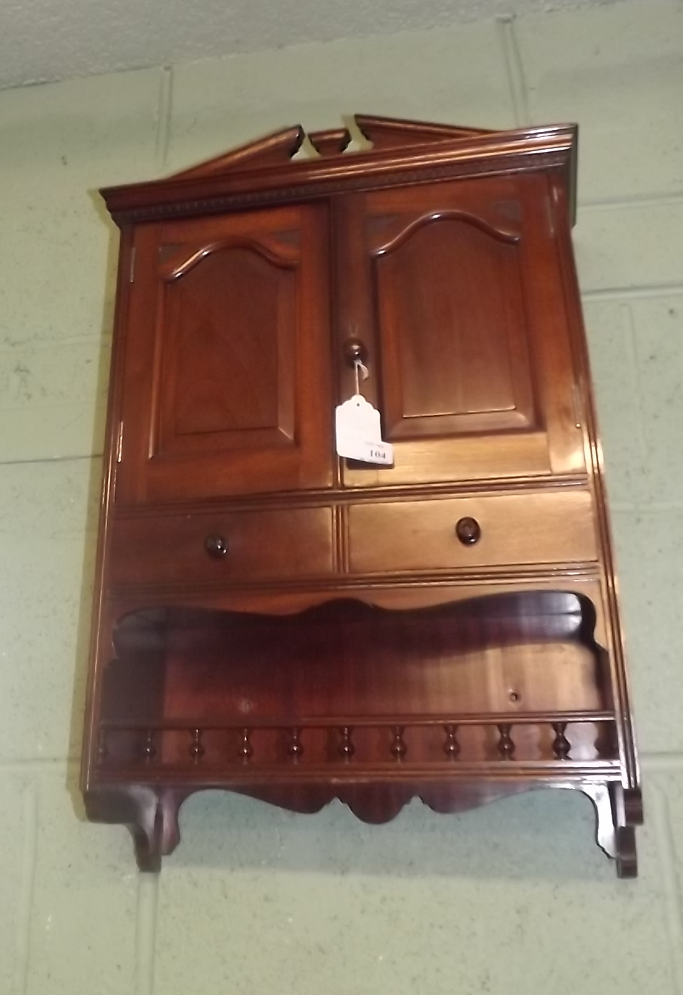 Mahogany hanging wall cabinet with two doors over two short drawers and shelf.