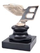 A Bentley Mk6 flying B radiator mascot. Plated silver, mounted probably as a desk ornament on a