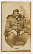 A sepia carte de visite photograph of Cetewayo, in European dress, wearing a fez and seated in an