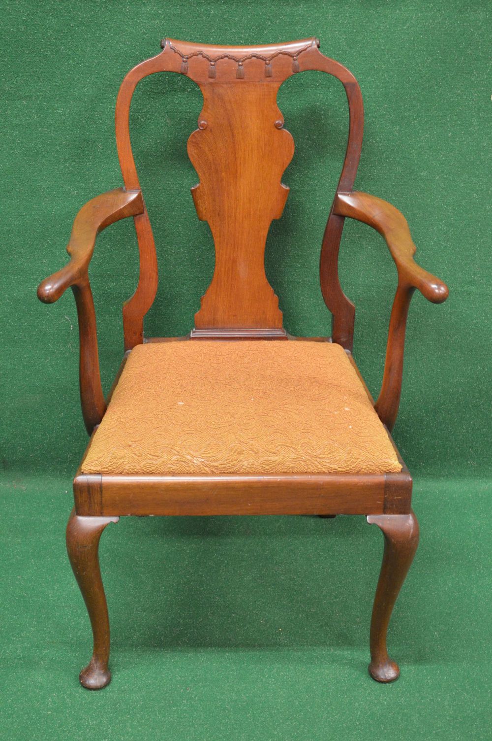 A Queen Anne style mahogany child's elbow chair the top rail carved with tassels over central back