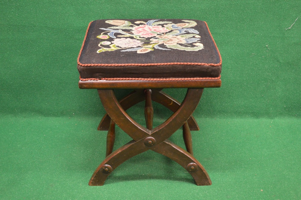 A square X frame dressing stool with padded seat embroidered with flowers and standing on an X frame