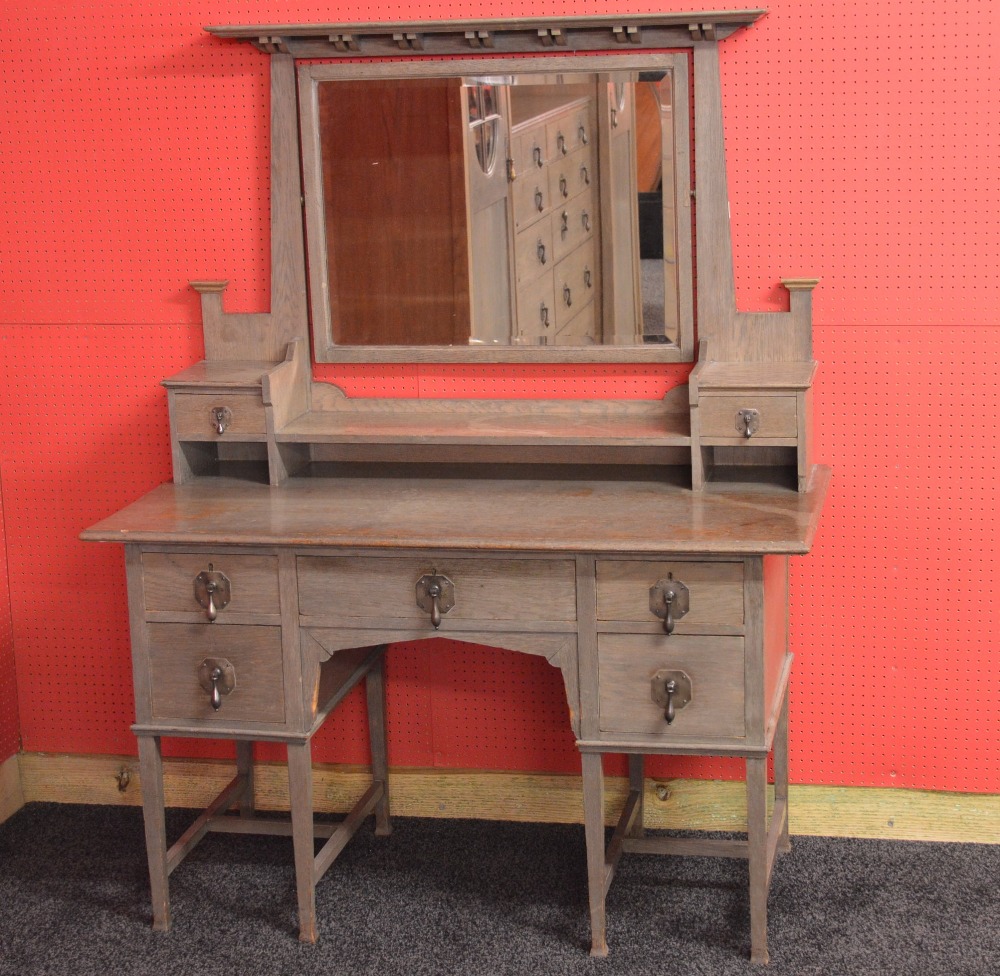 A Waring & Gillows Ltd Arts & Crafts limed oak dressing table having bevelled swing mirror flanked