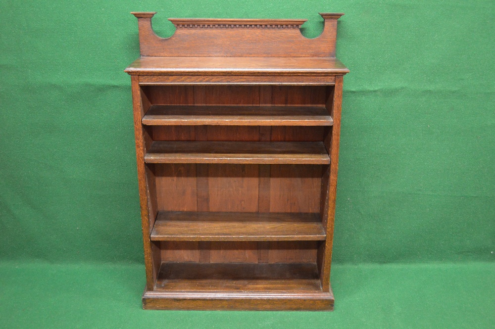 An oak bookcase having raised shaped back over moulded top and three adjustable shelves, standing on