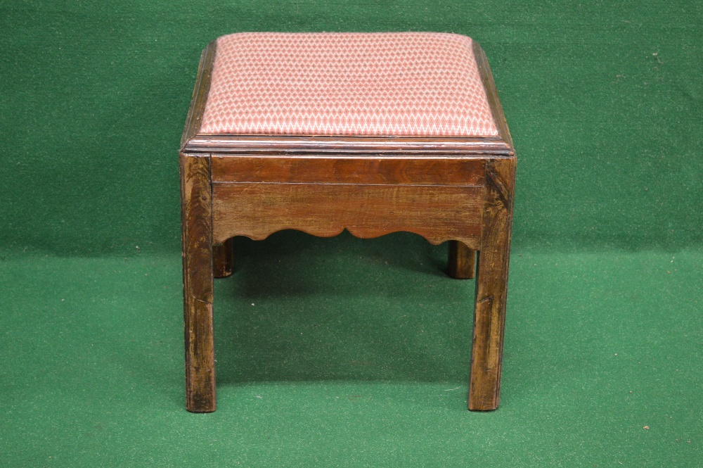 A Georgian mahogany square foot stool having padded seat over a shaped frieze and standing on square
