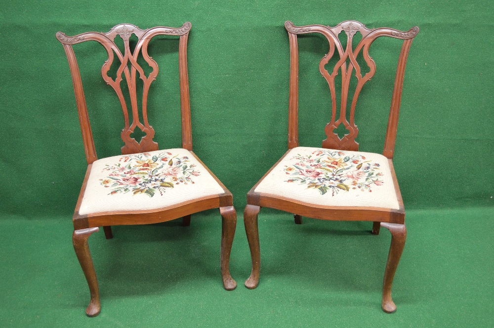 A pair of mahogany Chippendale style dining chairs with carved top rail over a pierced back splat