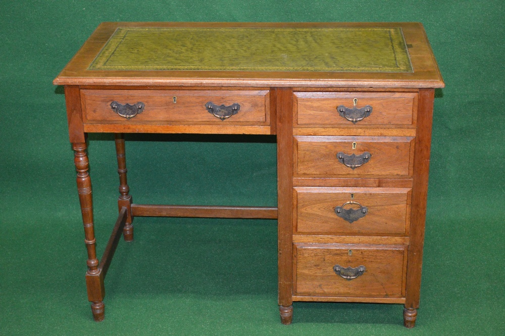 An Edwardian walnut writing desk having green leather insert over bank of four graduated right
