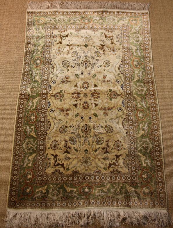 A Fine Persian Silk Rug. The ivory ground centre field woven with delicate  entwined scrolling stems