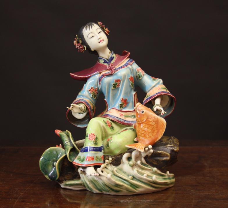 A Chinese 20th Century Porcelain Figure of  Girl sat on a rock with a golden carp to one side, lotus