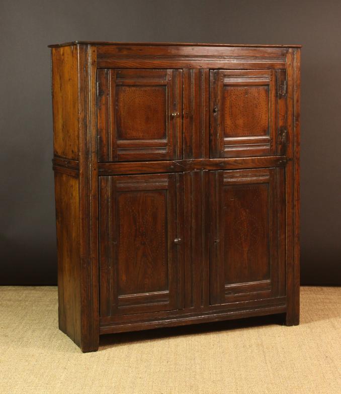 An Early 18th Century Joined Elm Food Cupboard.  The planked top above upper and lower twin-doored