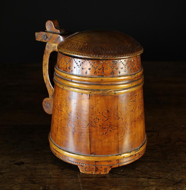 A Treen Peg Tankard decorated with poker work. The domed lid hinged to a scroll end handle on a