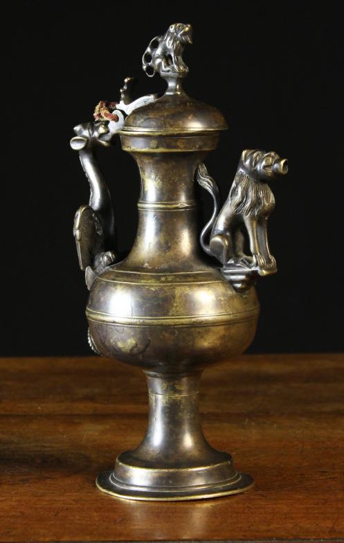 An Antique Bronze Ewer.  The bulbous vessel on a flared pedestal foot, having a domed lid surmounted