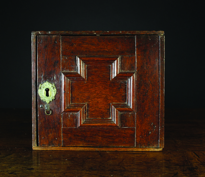 A Small 17th Century Oak Spice Cabinet.  The door having a geometric moulded cruciform panel with