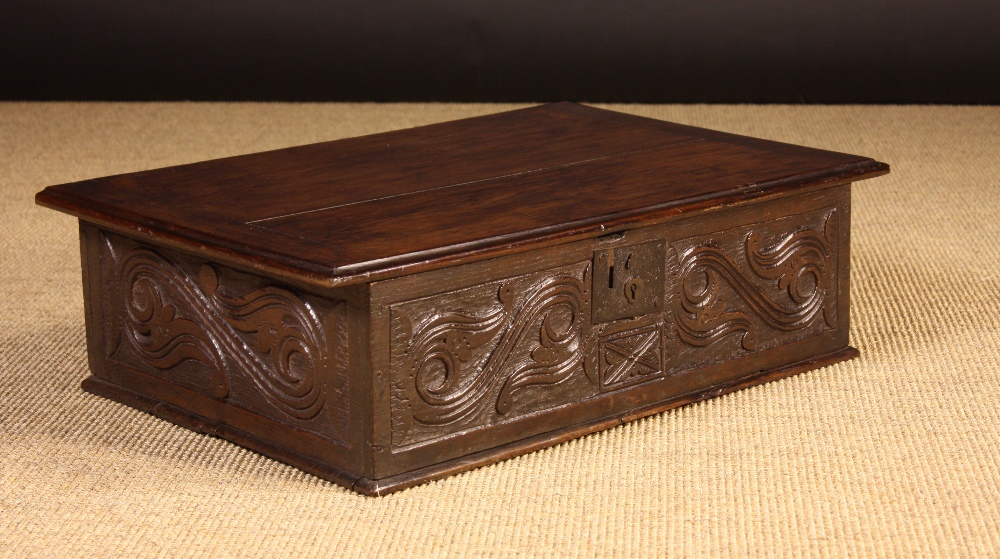 A 17th Century Boarded Oak Desk Box carved with foliated S-scrolls defined against a matted