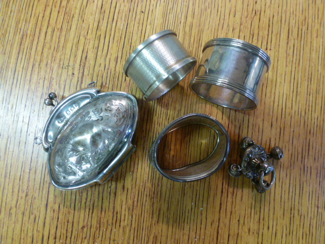 A silver purse, three napkin rings and a part rattle - Total weight approx. 3.5 troy oz.