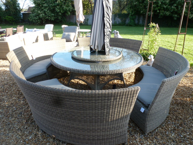 A Bramblecrest Sahara table with lazy susan and four benches, cushions, a parasol and base