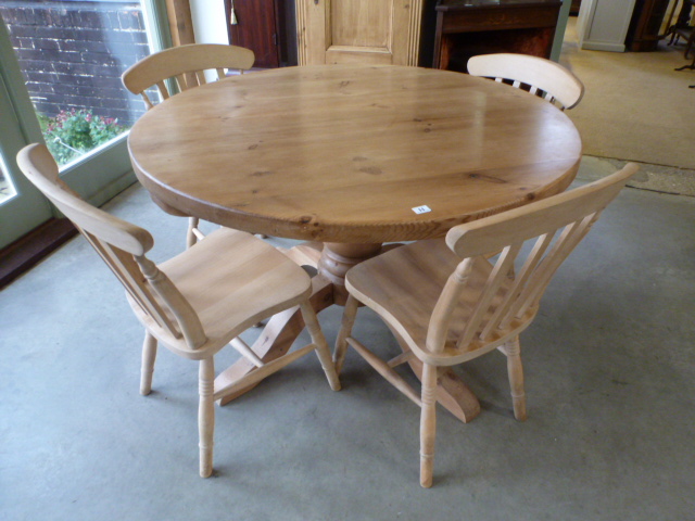 A modern pine circular dining table and four slat back chairs