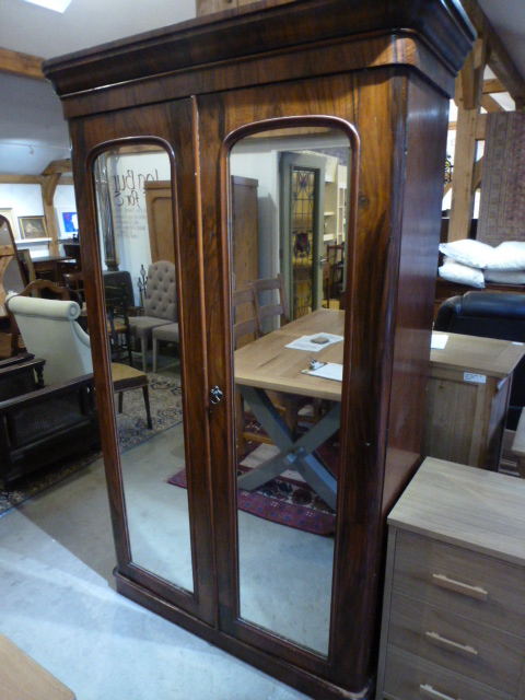 A Victorian walnut double wardrobe with two mirrored doors enclosing hanging space and a single