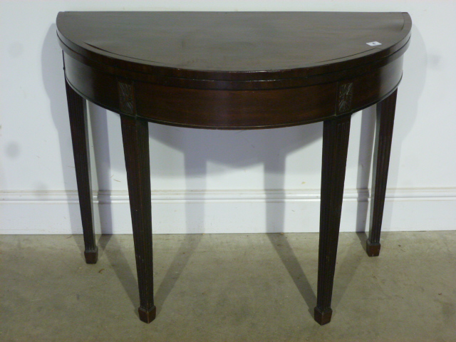 A 19th century mahogany foldover demi lune card table on reeded tapering legs