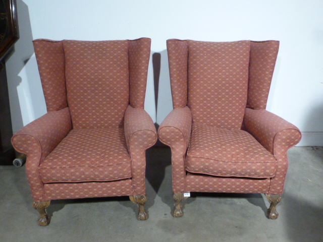 A pair of re upholstered wing back chairs on carved ball and claw feet