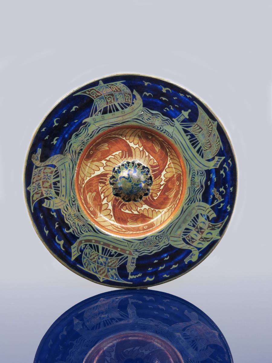 A William De Morgan Fulham triple lustre rice plate, painted to the well with four leaping fish in