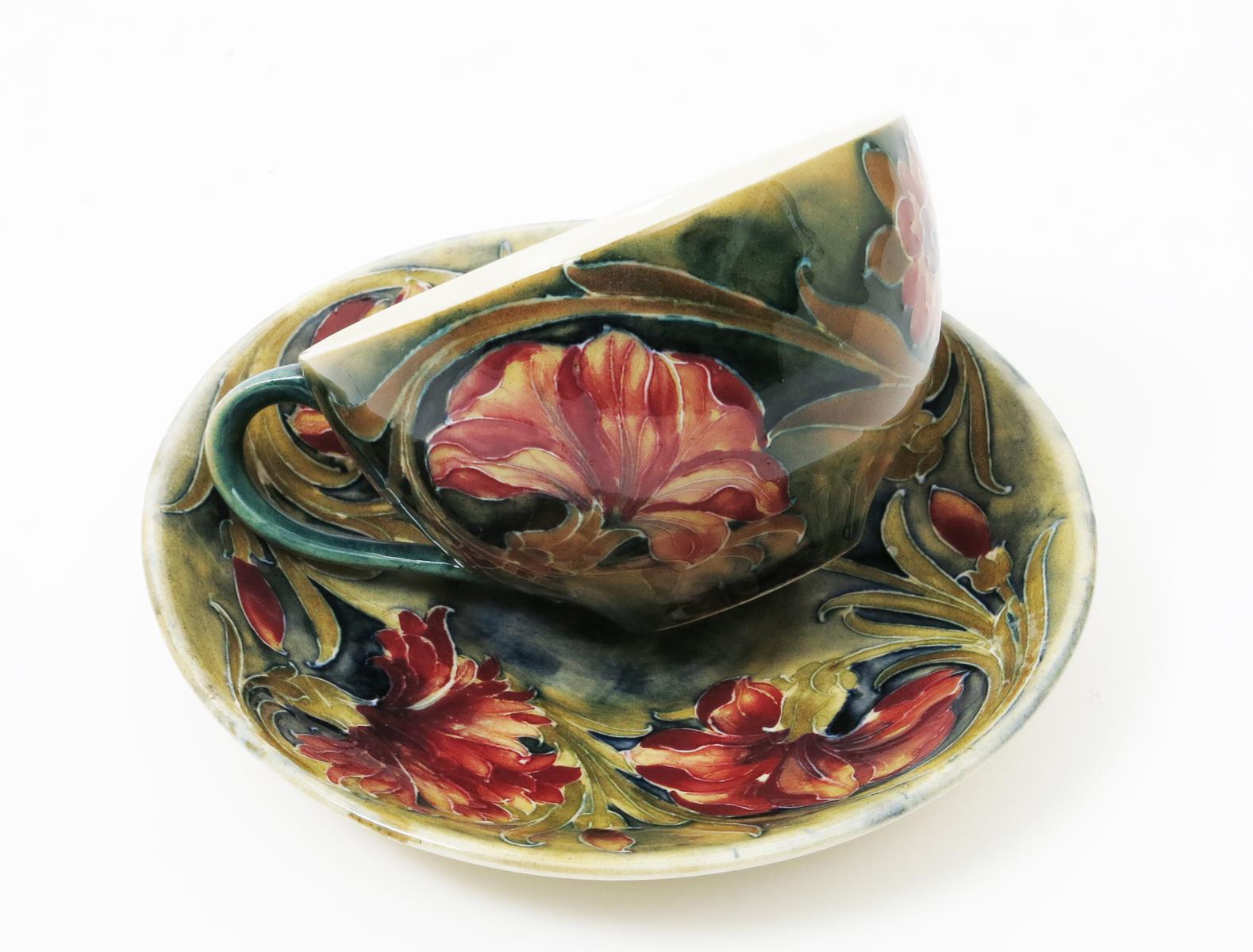 `Spanish` A Moorcroft cup and saucer designed by William Moorcroft, painted in shades of pink,