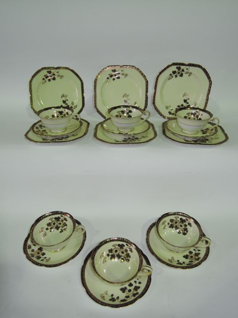 A collection of Noritake tea wares with black and gilt floral decoration on a pale yellow ground