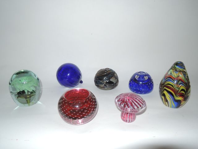 A selection of decorative glass items to include a heavy tear shaped paperweight with encased bands