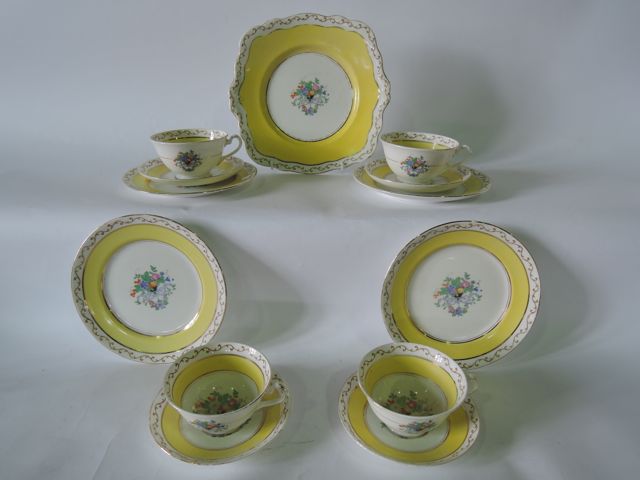 A collection of Foley China tea wares with printed and infilled floral decoration on a yellow and