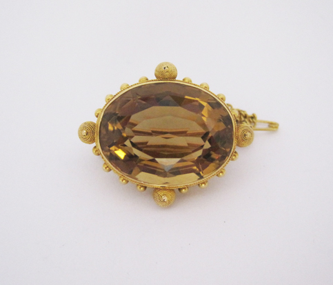 A CITRINE BROOCH the collet-set oval mixed-cut citrine weighing approximately 29.2cts, embellished