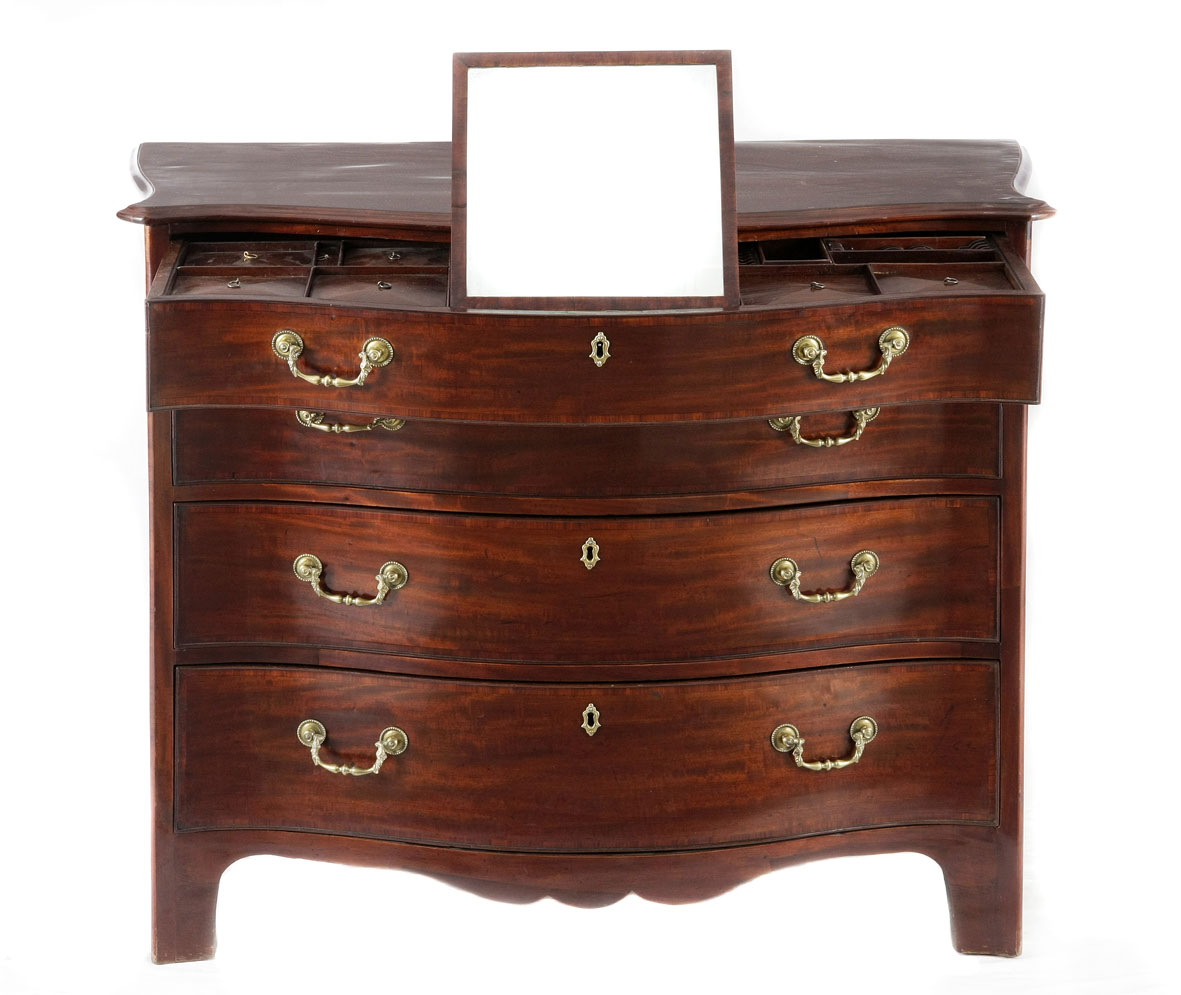 A George III mahogany Gentleman`s dressing chest the serpentine-shaped and crossbanded top above a