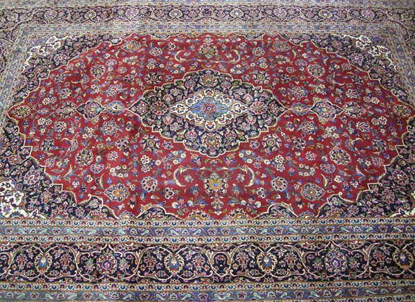 A Keshan carpet, Persia, modern the red field with a dark blue floral medallion and pendant, all