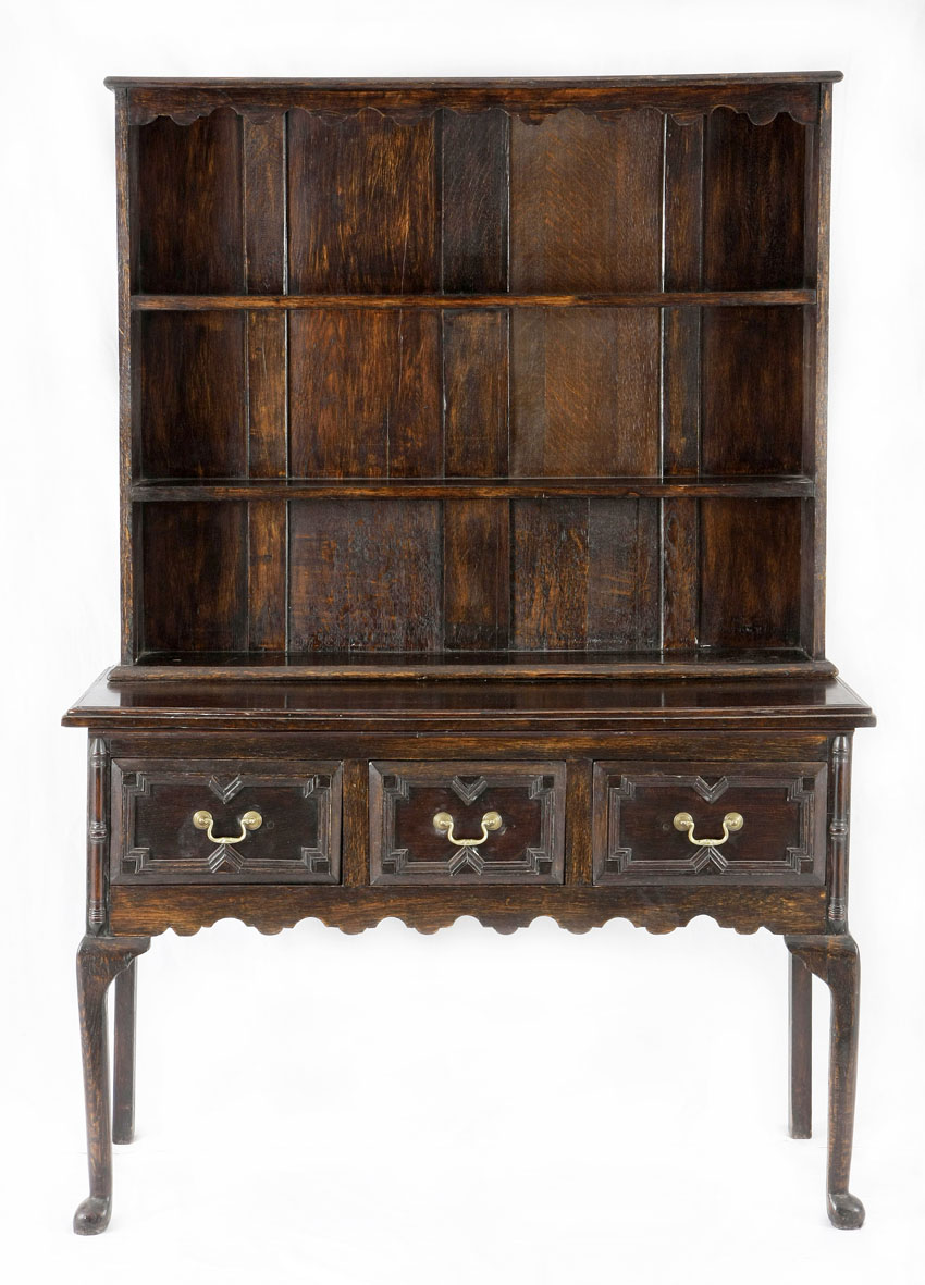 An oak dresser, 18th century  in two parts, the outset moulded pediment with a wavy frieze, three