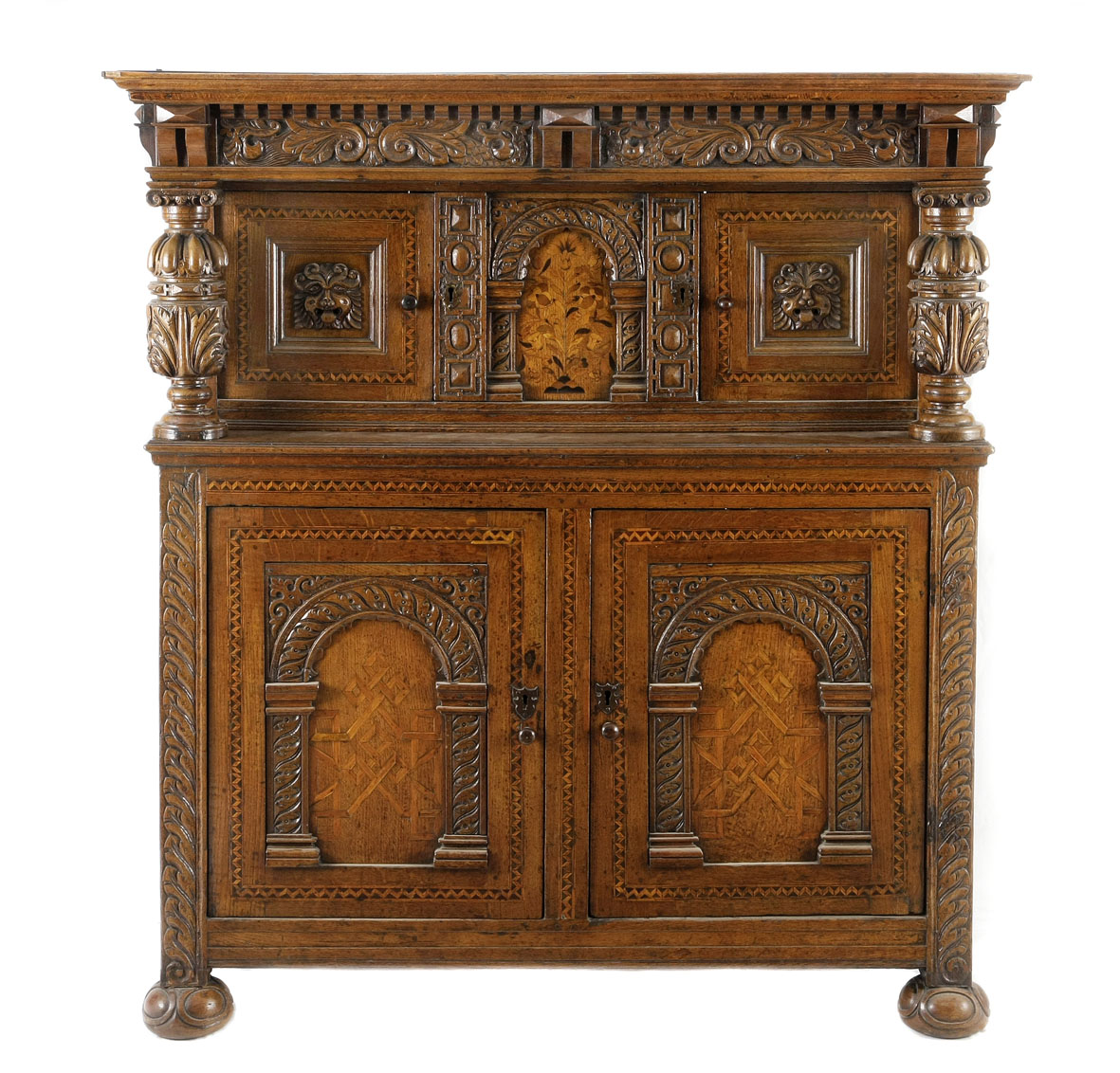 An Elizabethan carved oak and inlaid court cupboard the outset stepped pediment above an