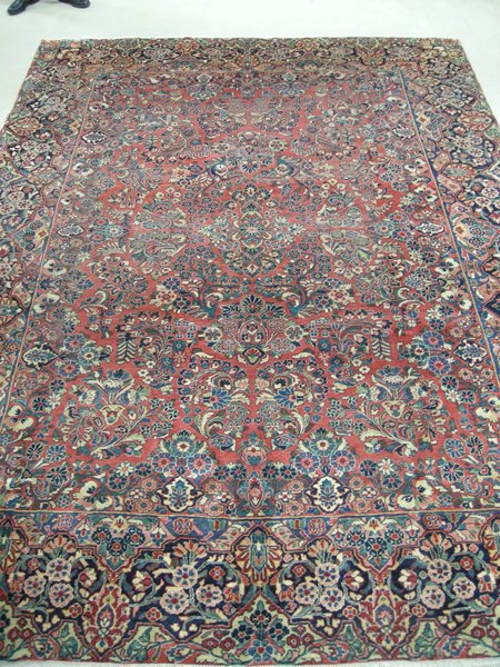 A Sarouk carpet, Persia the madder-red field with a small floral medallion all with polychrome