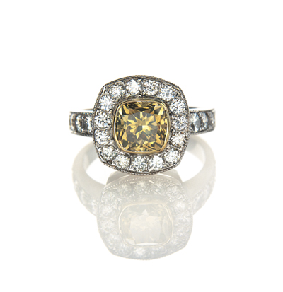 A DIAMOND RING centred with a collet-set yellowish-brown cushion-cut diamond weighing