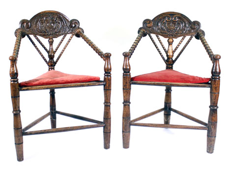 A set of four oak turner's chairs with carved top rails and triangular seats on turned legs