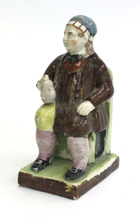 A figure of Tam o'Shanter, seated with an ale mug in his hand on a square base, h. 13.2 cm
