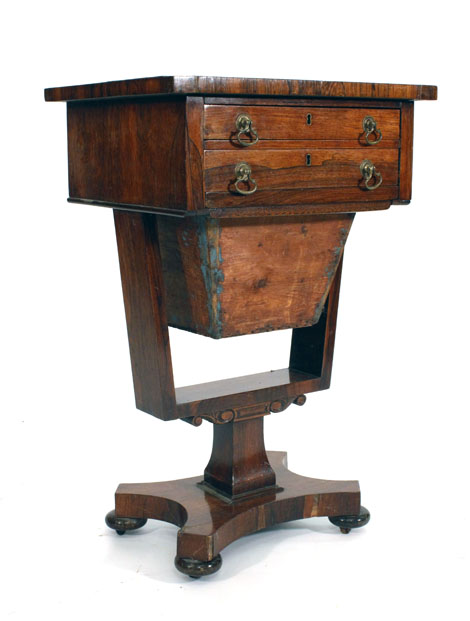 An early-19th century rosewood work table with two freize drawers above a basket slide on a platform