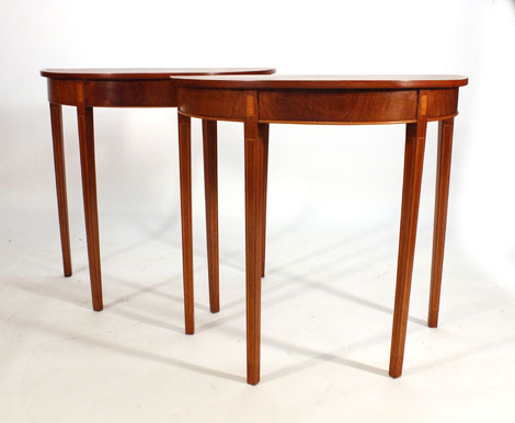 A pair of Sheraton-style walnut, satinwood, crossbanded and strung demi-lune tables on tapering