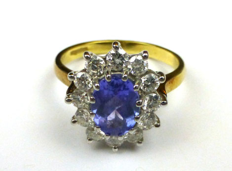 An 18ct yellow gold ring set centrally with an oval tanzanite within a border of twelve diamonds,